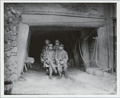 Miners on ore cars in tunnel
